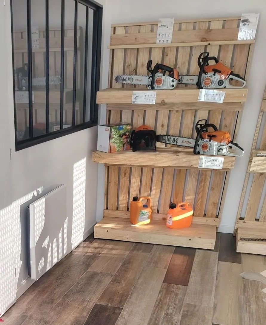 Les étagères en bois du magasin avec les tronçonneuses STIHL exposées, les bidons et les équipements de protection