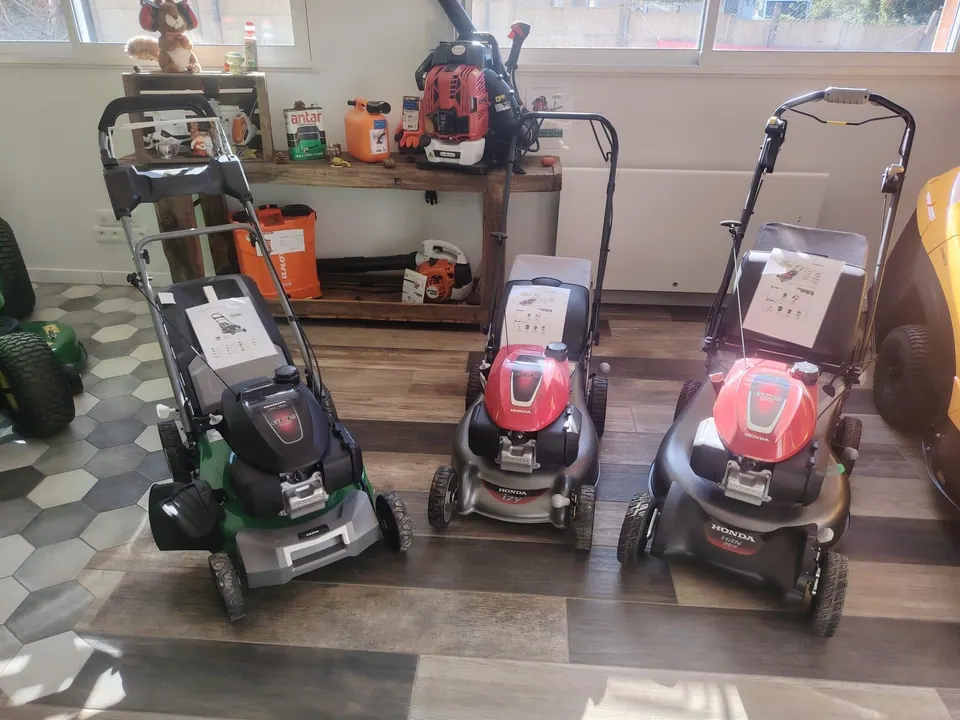 Le pôle tondeuses du magasin : trois tondeuses thermiques Honda devant l’établi